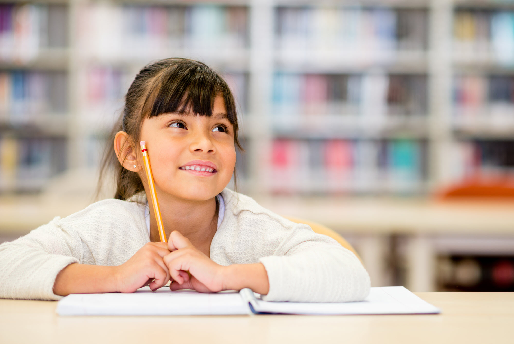 elementary school girl smiling and holding a pencil