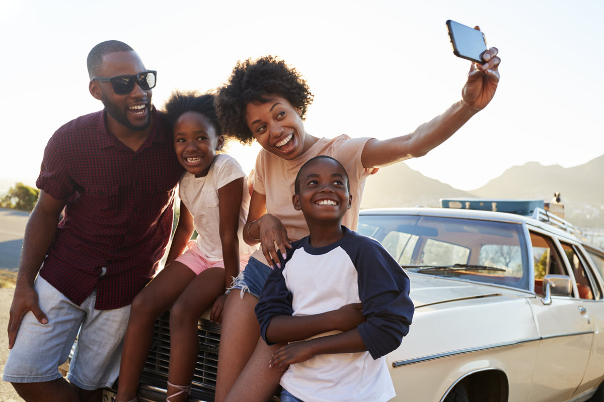 smiling family taking a selfie on a car