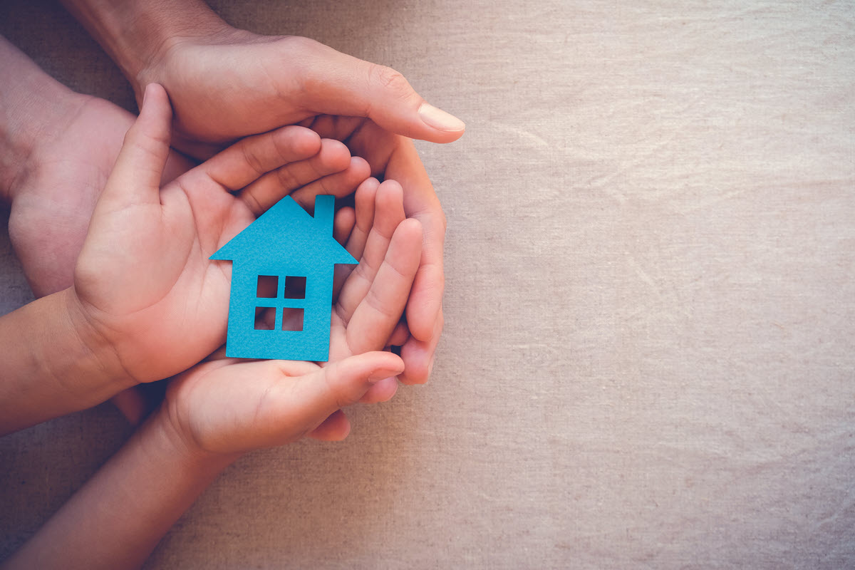 hands holding a paper house cutout