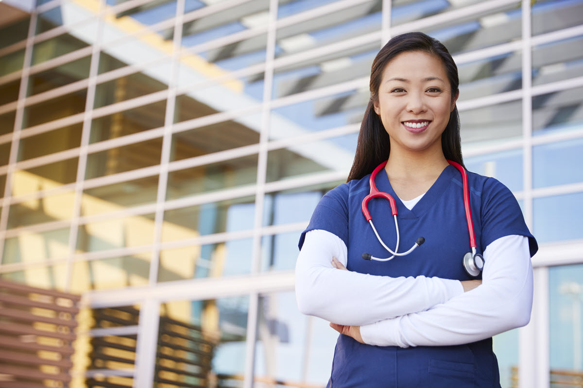 female nurse smiling with arms crossed for health insurance