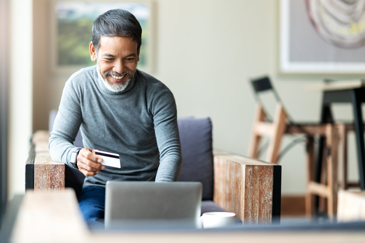 older man in front of computer with credit card