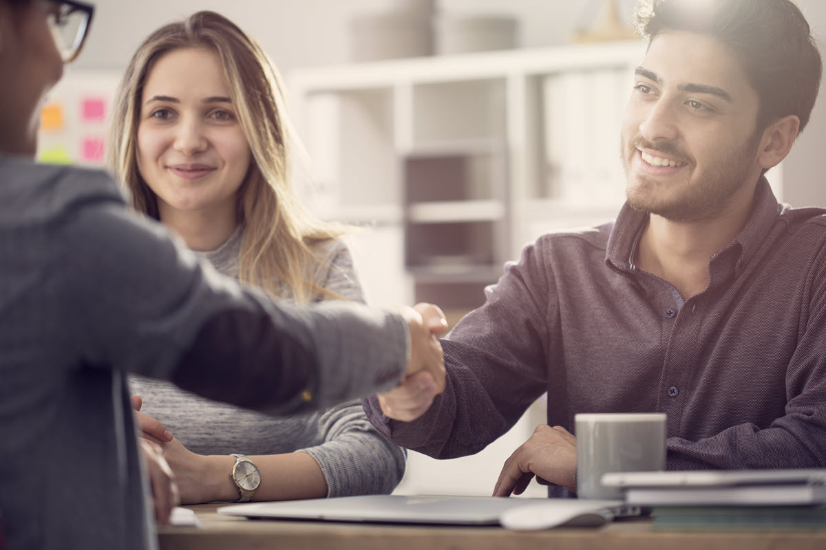 couple shaking hands with banker